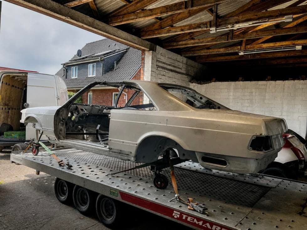Blanke Karosserie eines Mercedes 500 SEC (C126) auf dem Transportanhänger – Beginn einer SGS-Restauration